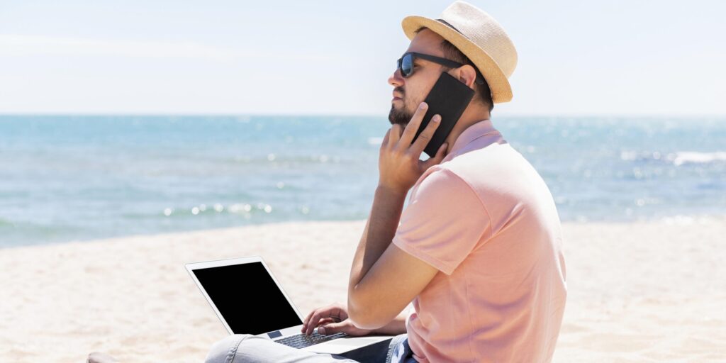 Hombre trabajando desde la playa con su centralita virtual